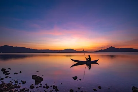 person in a boat by sunset