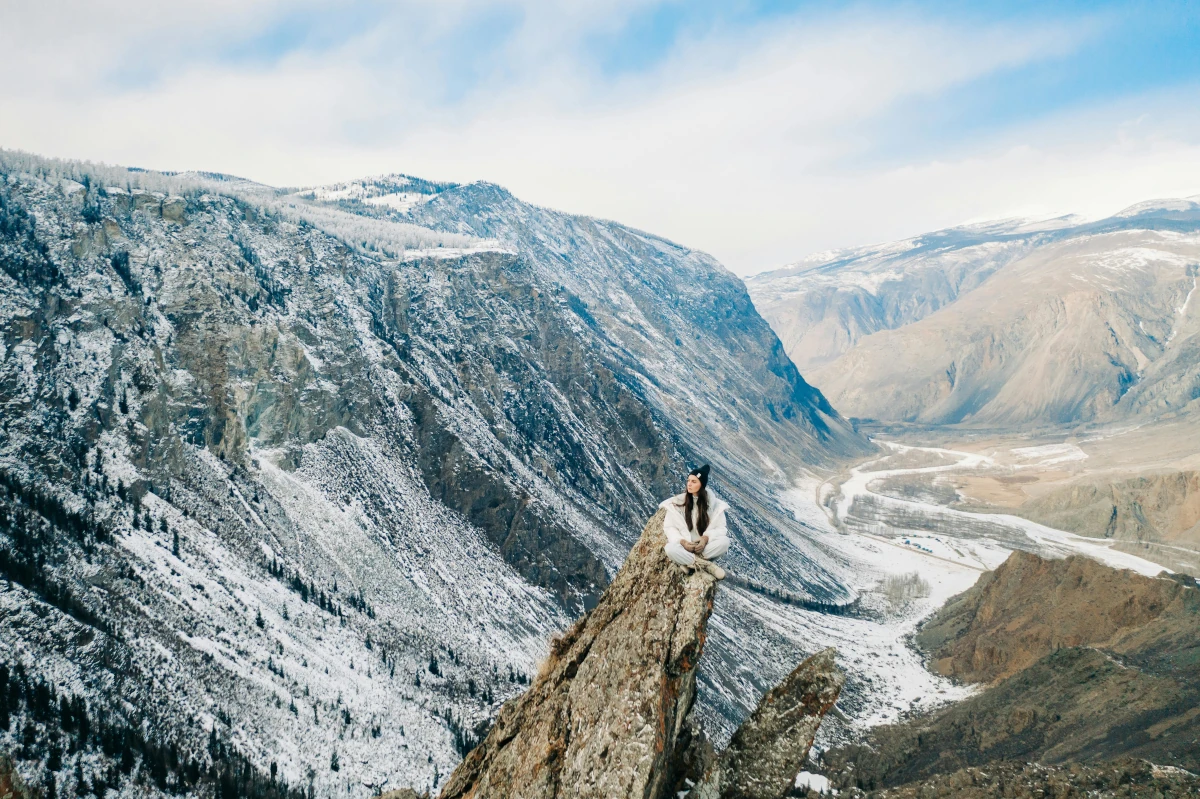 best-camping-adventures-in-europe-a-woman-sitting-high-above-on-a-rock