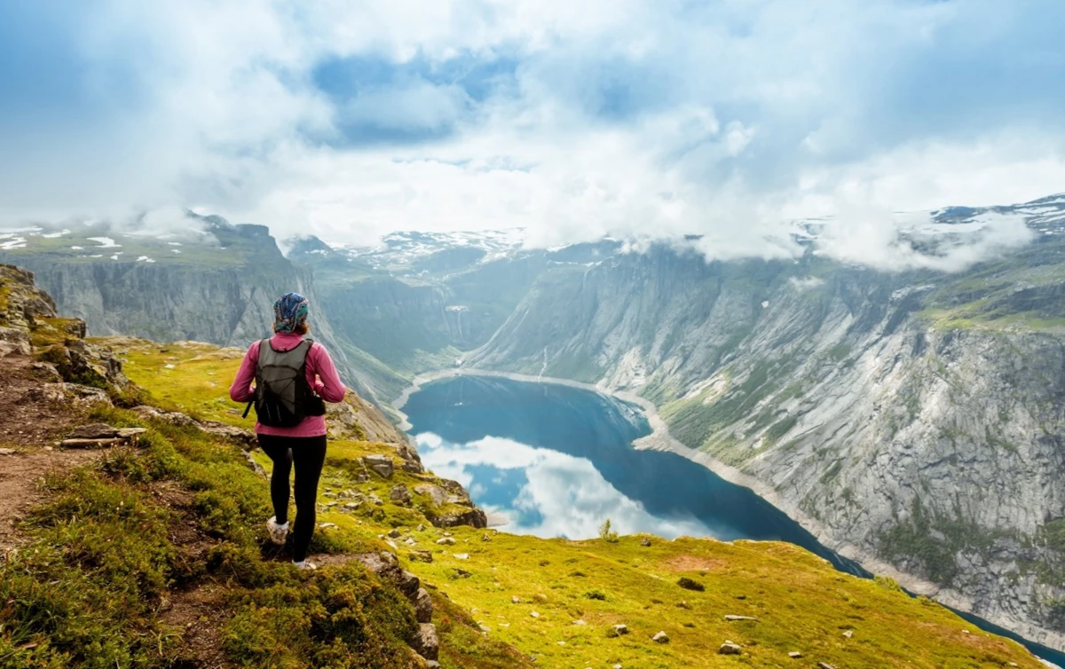 female hiker standing on mountain overlooking a lake